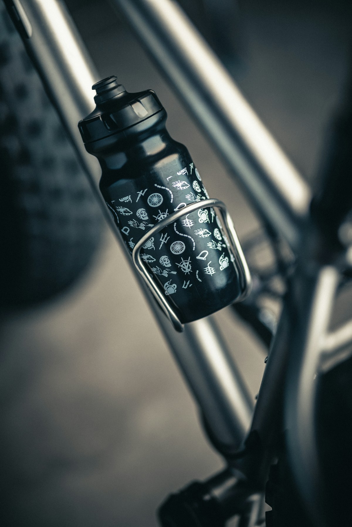Patterned matte bidon clipped into a polished titanium cage on an adventure-ready frame