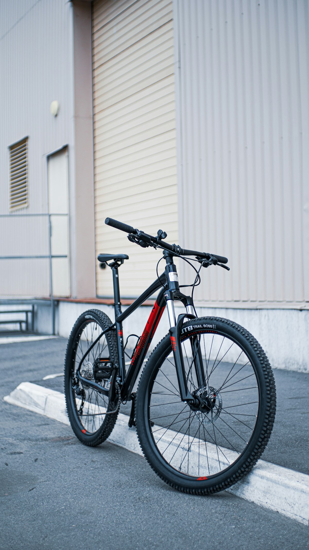 Black and lava-orange road bicycle parked perpendicular to crisp white corrugated architecture